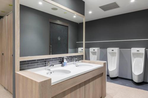 a bathroom with two sinks and a mirror and urinals at TUBE Sq in Tokoname