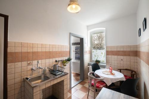 eine Küche mit einem Waschbecken, einem Tisch, einem Tisch und einem Tisch in der Unterkunft Miliő Apartman Badacsony in Badacsonytördemic