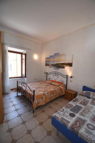 a bedroom with two beds and a window at Bilocali ALTAMAREA - zona mare con clima e terrazze in Marina di Campo
