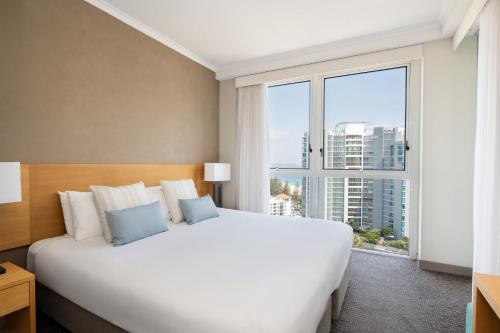 a large white bed in a room with a large window at Mantra Twin Towns in Tweed Heads