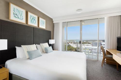 a bedroom with a large white bed and a desk and window at Mantra Twin Towns in Tweed Heads