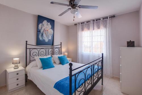 a bedroom with a bed with blue pillows and a ceiling fan at Apartamento Callao Salvaje in Callao Salvaje