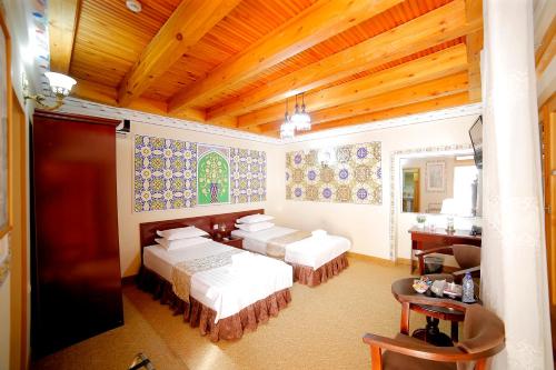 a bedroom with three beds and a wooden ceiling at Kavsar Boutique Hotel in Bukhara