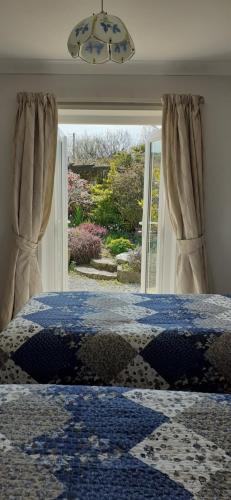a bedroom with a bed and a large window at West Point B&B in Bude