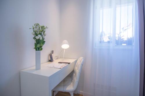a white desk with a vase of flowers and a lamp at Divota Apartment Hotel in Split