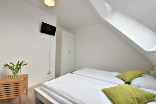 ein Schlafzimmer mit einem weißen Bett und grünen Kissen in der Unterkunft Ferienhaus Backbord und Steuerbord OFC 10 in Börgerende-Rethwisch