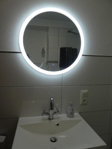 a bathroom sink with a round mirror above it at Ferienwohnung Am Hirschpark in Bad Pyrmont