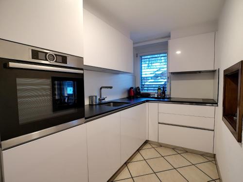 a white kitchen with a sink and a microwave at L'Attila - Big and cozy flat in the Center 7 beds in Zermatt