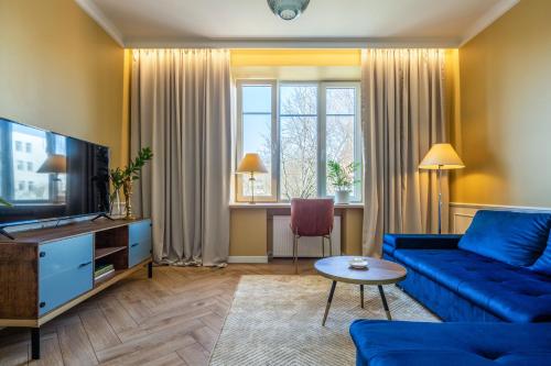 uma sala de estar com um sofá azul e uma televisão em LIVING & LIFESTYLE home - Klaipeda - by Hello Sea homes em Klaipėda