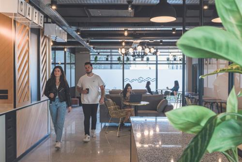 een man en vrouw die door een gang lopen in een gebouw bij Whoo Bordeaux Bacalan - Hostel in Bordeaux