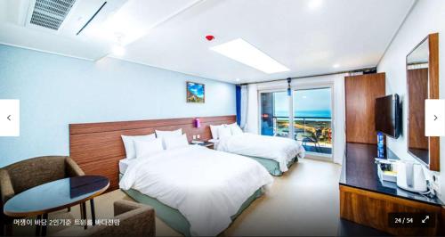una camera d'albergo con due letti e una televisione di The Stay Century Hotel a Jeju