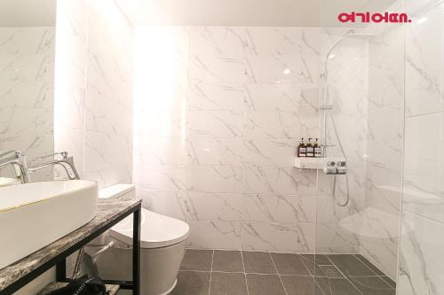 a white bathroom with a shower and a toilet at De Homme Hotel in Busan