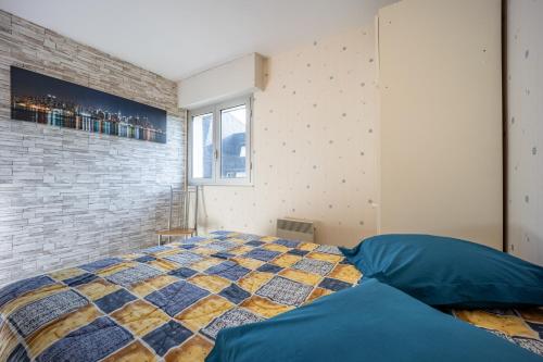 een slaapkamer met een bed en een bakstenen muur bij Le Pavois - appartement à 50 mètres de la mer in Bernières-sur-Mer