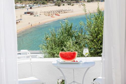 a glass of wine and a slice of watermelon on a table on a balcony at Ios Palace Hotel & Spa in Mylopotas