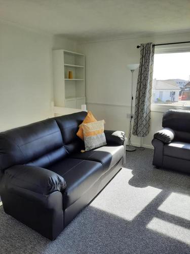 a black leather couch in a living room with a window at 2 Storey 3 Bedroom Chalet -Outdoor Swimming Pool - sleeps up to 6 - 5 min walk to the Beach, near Broads and Great Yarmouth in Scratby
