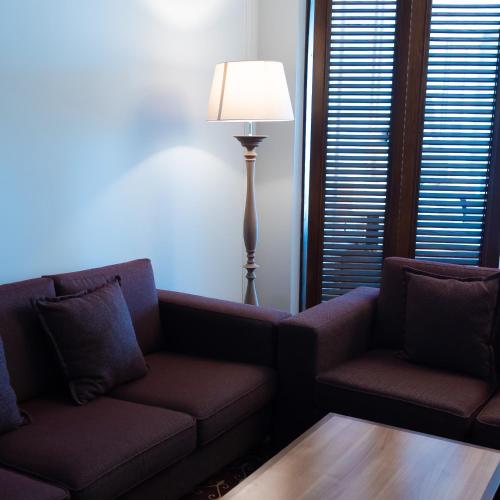 a living room with two couches and a lamp at Jumbaktas Astana Hotel in Astana