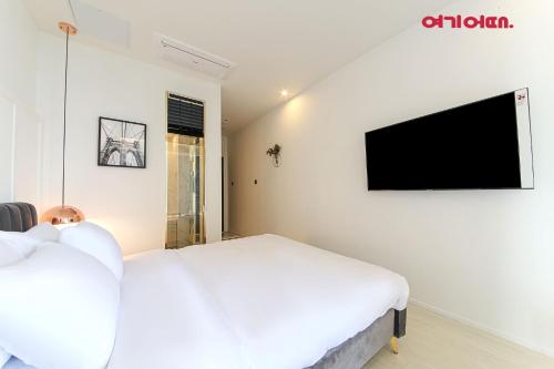 a bedroom with a bed and a tv on the wall at De Homme Hotel in Busan