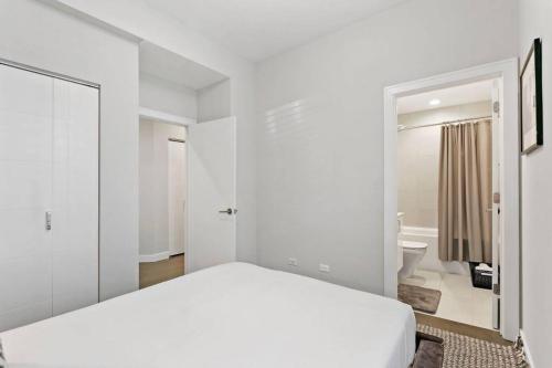 a white bedroom with a bed and a bathroom at Cozy & Modern 3BR Apartment - Division 201W in Chicago