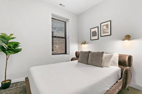 a white bedroom with a bed and a potted plant at Cozy & Modern 3BR Apartment - Division 201W in Chicago