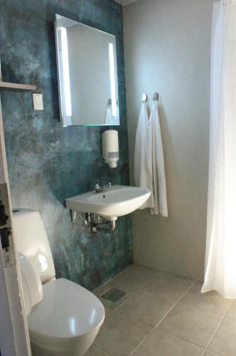 a bathroom with a sink and a toilet and a mirror at STAY and SLEEP Grindsted - Billund in Grindsted