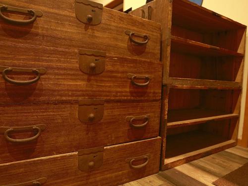 a wooden dresser with drawers and shelves at HOSTEL Co-EDO in Katori