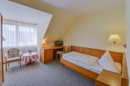 Schlafzimmer mit einem Bett, einem Schreibtisch und einem Stuhl in der Unterkunft Landhaus Braband in Cuxhaven
