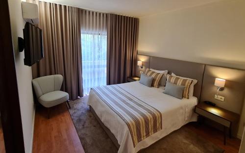 a hotel room with a bed and a television at Hotel Eden in Luso