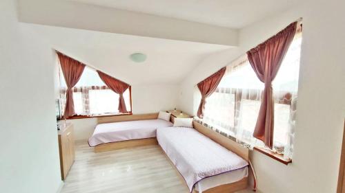 a bedroom with two beds and two windows at Къща за гости Орфей in Smolyan