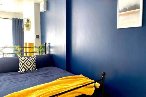 a blue bedroom with a bed with a yellow blanket at Stylish, cosy studio in Carmarthen town centre in Carmarthen