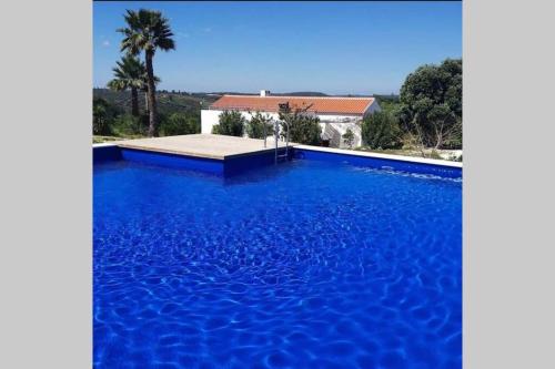 a large blue swimming pool in front of a house at Quinta dos Malhadais, Figueira - Farm house in Portimão