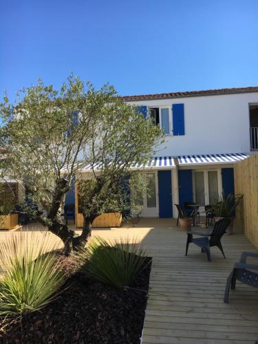 une terrasse en face d'un bâtiment avec un arbre dans l'établissement Les Bains Boyardville - Hôtel et Restaurant, à Boyardville