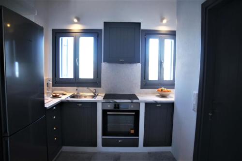 a kitchen with black cabinets and a sink at Krotiri View Paros in Krotiri