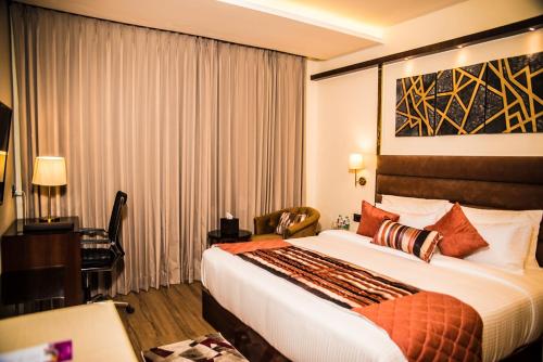 a hotel room with a large bed and a desk at Regenta Inn Amristar Airport Road by Royal Orchid Hotels Limited in Amritsar