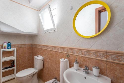 a bathroom with a white toilet and a yellow mirror at Apartamento Pintada 25 in Nerja
