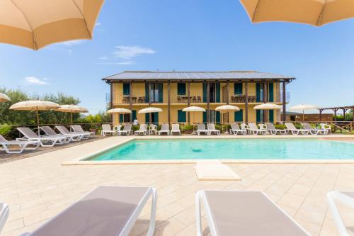 a resort with a pool and chairs and a building at Casale del Conero in Porto Recanati