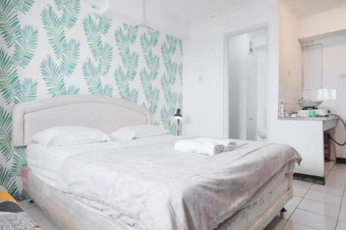 - une chambre avec un lit blanc et un mur vert verdoyant dans l'établissement Apartemen Sentra Timur Residence - Cheap Inn Tower Orange, à Jakarta