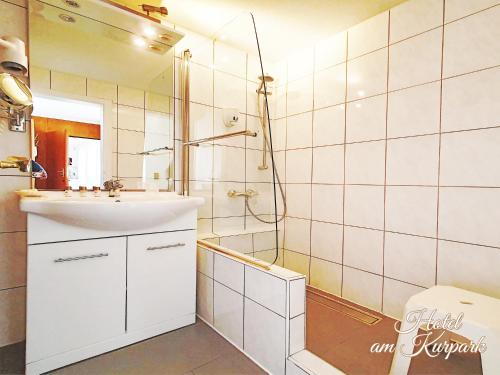 a white bathroom with a sink and a shower at Hotel am Kurpark in Bad Wimpfen