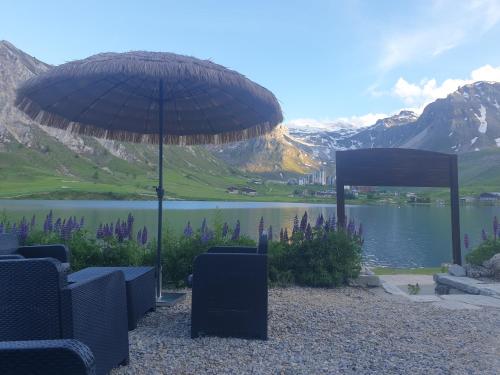 an umbrella and chairs in front of a lake at Le Terril Blanc in Tignes