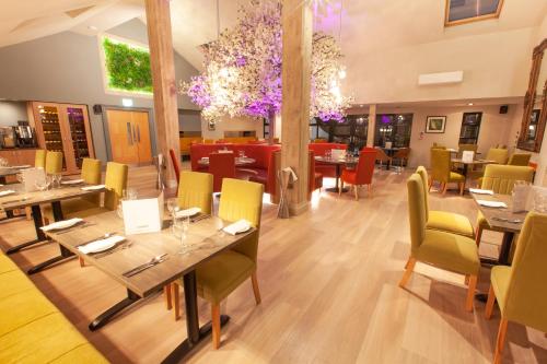 a restaurant with wooden tables and chairs and purple flowers at Best Western Plus White Horse Hotel in Derry Londonderry
