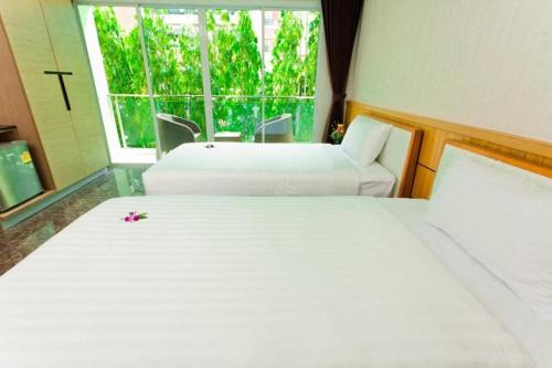 two white beds in a room with a window at Anda Beachside Hotel in Karon Beach