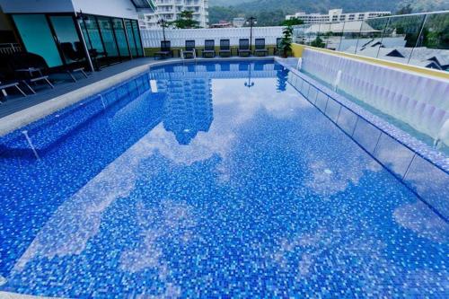a large blue swimming pool with a reflection in the water at Anda Beachside Hotel in Karon Beach