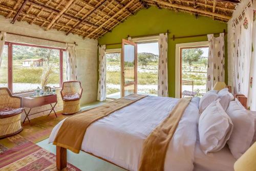 a bedroom with a large bed in a room with windows at Camp Lands End in Pushkar