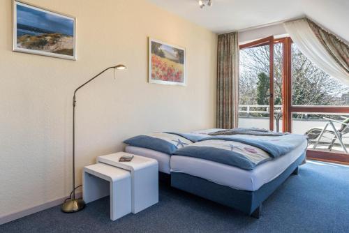 a bedroom with a bed and a window at Schau-ins-land Fewo Wenningstedt in Wenningstedt