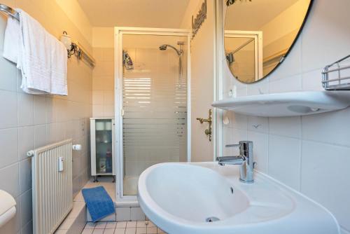 a white bathroom with a sink and a shower at Schau-ins-land Fewo Wenningstedt in Wenningstedt