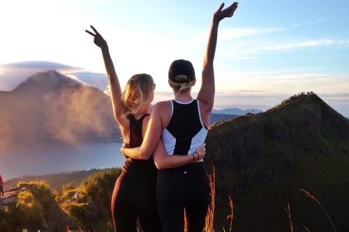 two women standing on top of a mountain with their arms in the air at The Breezy Volcano in Kintamani