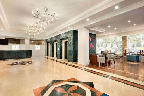 a lobby with a chandelier and a dining room at Wyndham Tashkent in Tashkent