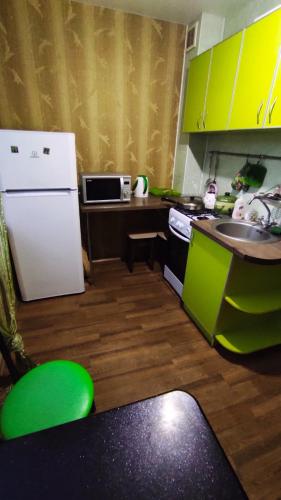 a kitchen with green cabinets and a white refrigerator at Комфортные аппартаменты возле метро Студенческая in Kharkiv