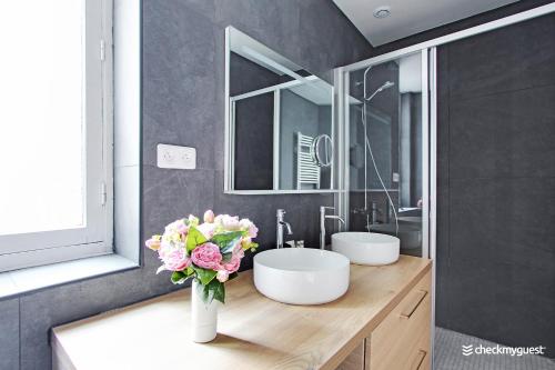 a bathroom with two sinks and a vase of flowers at CMG - Place des Vosges in Paris