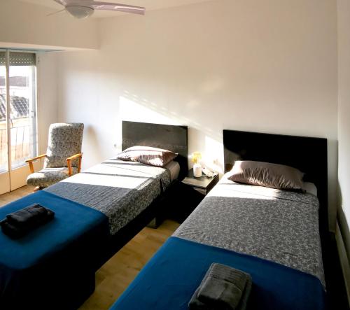 a bedroom with two beds and a chair at Piso De Balboa Wi-Fi, Air-Con in Gandía