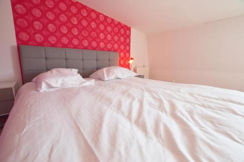 a bedroom with a large white bed with a red wall at Capstay Cosy centre 2 chambres babyfoot & Netflix in Raismes
